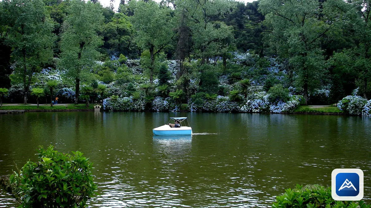 Lago Negro em Gramado cercado por árvores e hortênsias, com um barco no lago